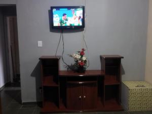 a tv on a wall with a vase of flowers at Casa completa para 4 pessoas in Itu