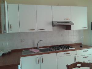 ポルトパーロにあるCasa Mercurioのキッチン(白いキャビネット、シンク、コンロ付)