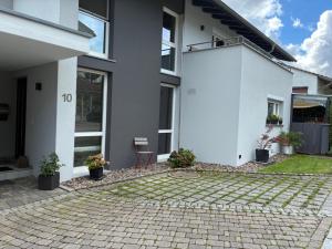 a white house with potted plants and a patio at FeWo Silence&View in Weilheim