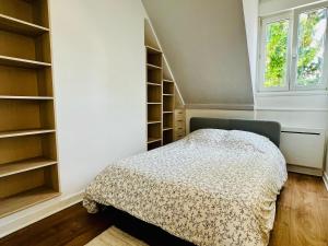 een slaapkamer met een bed, planken en een raam bij Appartement calme et spacieux, tout équipé in Saint-Quentin +9 foto's