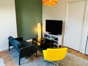 een woonkamer met een bank en een televisie bij Appartement calme et spacieux, tout équipé in Saint-Quentin