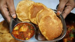 a person is holding a plate of food with food at Hotel ShivKashi Inn in Varanasi
