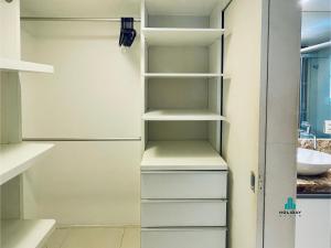 a walk in closet with white shelves and a sink at Loft Praia by Holiday Stays in Fortaleza +5 photos