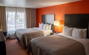 two beds in a hotel room with orange walls at Quality Inn & Suites Fresno Northwest in Fresno