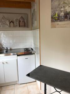 a small kitchen with white cabinets and a table at Le clos de la Pommeraie maisonnette in Carly +8 photos