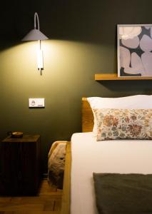 Un dormitorio con una cama y una lámpara en la pared. en Ruby Hostel - Lux Group Dorm Rooms, en Kutaisi
