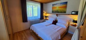a bedroom with a white bed and a window at Ferienwohnung am Krausberghof mit Balkon und Parkplatz, Aufenthaltsraum mit Spielmöglichkeiten, Erholung- inmitten der Natur, 6 Fahrminuten zur Alpentherme Gastein und zur Schlossalmbahn in Bad Hofgastein
