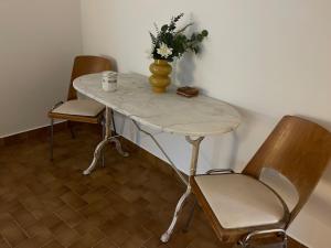 a table with a vase of flowers and two chairs at 2 rooms with garden in Longchamp-sur-Aujon