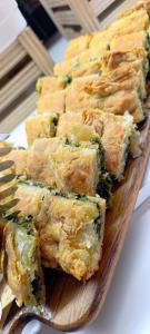 a wooden cutting board topped with broccoli and cheese food at Hotel Thermaikos in Korinos