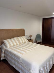 a bedroom with a large bed with a striped blanket at El rincón de Carolina in O Barqueiro