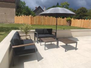 a patio with two couches and an umbrella and tables at Maison Louise - Gîte de charme entre forêt et étang - Family friendly 