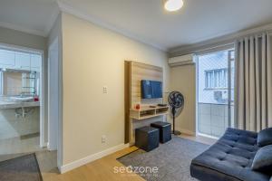Una sala de estar con un sofá y un televisor. en Apto funcional a 120m de la playa en BC | CEC0302, en Balneário Camboriú