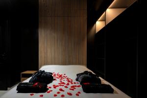 a bed with red petals on it in a room at Obsidian Luxury Suite - balnéo, miroirs aux plafonds, proche disney in Montévrain