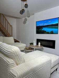 a living room with white furniture and a flat screen tv at Escapade dans le Jura 