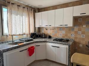 a kitchen with white cabinets and a sink at Appartement arome in Rabat