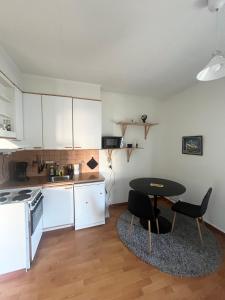 a kitchen with white cabinets and a table and chairs at Snygg studio lägenhet Wolffskavägen 21 in Vaasa +1 photo
