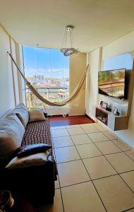 a living room with a couch and a large window at Apartamento com 2 quartos próximo aCastelão Arena in Fortaleza