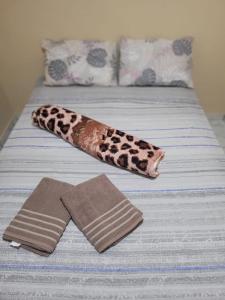 a bed with a leopard blanket and a pair of towels at Pesqueiro e Pousada Arena in Guararema