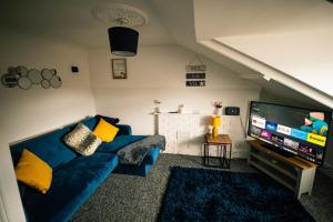 a living room with a blue couch and a flat screen tv at One Bedroom Apartment By Eason Stays Short Lets & Serviced Accommodation Lowestoft With Beach View in Lowestoft