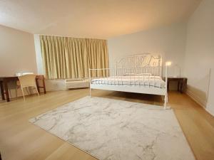 a bedroom with a white bed and a rug at Idlewood Inn in Toronto