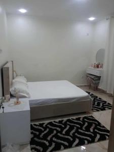 a white bedroom with a bed and a mirror at appartement T2 in Fort de lʼEau