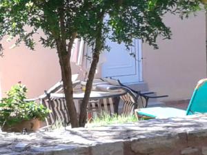 eine Terrasse mit einem Tisch, Stühlen und einem Baum in der Unterkunft Ktima Tzamika in Strand Episkopi-Rethymnon