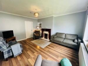 a living room with a couch and a television at Coll’s Dachaigh in Inverlochy
