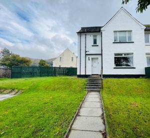a white house with a white door in a yard at Coll’s Dachaigh in Inverlochy