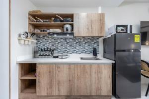 a kitchen with a black refrigerator and wooden cabinets at Cebu Serene Quarters with Pool View in Mactan Island