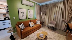 ein Wohnzimmer mit einem braunen Sofa und einer grünen Wand in der Unterkunft Apto Novo próximo Maria Fumaça in Bento Gonçalves + 17 Fotos