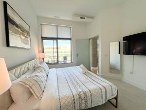 ein Schlafzimmer mit einem weißen Bett und einem Fernseher in der Unterkunft The Crestwood Loft 2BR 3Beds in Odricks Corner