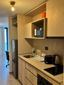a kitchen with a sink and a refrigerator at Departamento nuevo a pasos del metro irrarazaval in Santiago