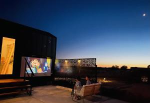 a man sitting in a chair in front of a screen at ART HAUS Grand Canyon South Rim - Hot Tub, Hammock, Movie Projector, Telescope in Valle