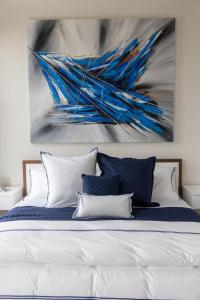 a bed with blue and white pillows and a painting at Lofty Blues at the Brent Lofts in Baptist Hospital Heliport