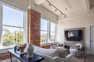 a living room with white furniture and a brick wall at Palafox Oasis in Baptist Hospital Heliport