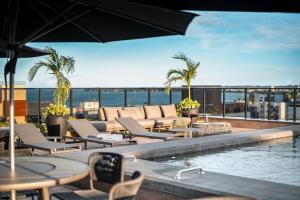 a hotel patio with a pool and chairs and the ocean at Flat novo, moderno e super bem localizado in Tambaú