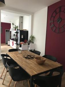 a dining room table with chairs and a clock on the wall at Loft 11 personnes Sauna Jacuzzi in Mouscron