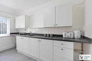 a kitchen with white cabinets and a black counter top at Abbie's House in Nottingham