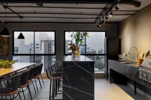 a kitchen with a black counter and some chairs at Flat novo, moderno e super bem localizado in Tambaú