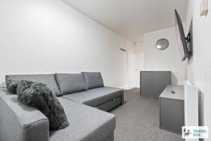a living room with a gray couch and a clock at Abbie's House in Nottingham