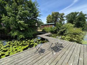 a wooden deck with two chairs on a pond with lilies at Cottage - Kleine alte Villa am See in Bestensee