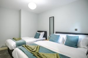 a bedroom with two beds with blue pillows at Modern 2 Bed Flat, Wifi, Parking, Self Check-in, Sleeps 5, 2 bathrooms, Close to Stepping Hill & Motorways in Stockport