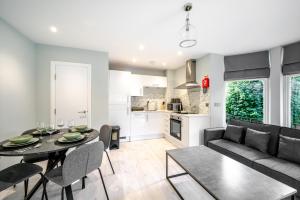 a living room and kitchen with a table and a couch at Modern 2 Bed Flat, Wifi, Parking, Self Check-in, Sleeps 5, 2 bathrooms, Close to Stepping Hill & Motorways in Stockport