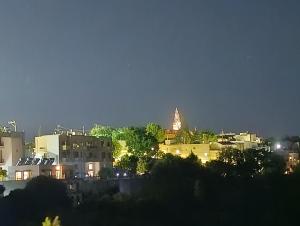 a city at night with a clock tower in the distance at Anemomilos View in Koskinou