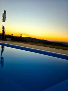 Cabanas do Rancho - Lazer & Eventos em São Roque في ساو روكي: غروب الشمس على مسبح مع نخله +54 صورة