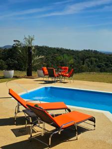 Cabanas do Rancho - Lazer & Eventos em São Roque في ساو روكي: مجموعة من كراسي الاسترخاء البرتقالية وحمام السباحة