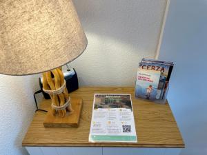 a table with a lamp and a magazine on it at L'ALOUETTE maison 4/5pers PISCINE/MER Cabourg à pied in Dives-sur-Mer +27 photos