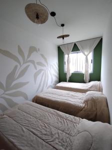 2 letti in una camera da letto con pareti verdi e bianche di Miatello a Villa Nueva