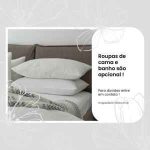 uma foto de uma cama com travesseiros em Hospedaria Vitória Mar em Ubatuba
