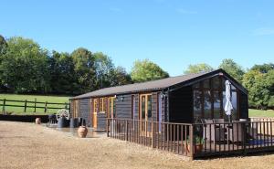 a black cabin with a fence in a field at Stable lodge 2 Bedrooms in Horspath